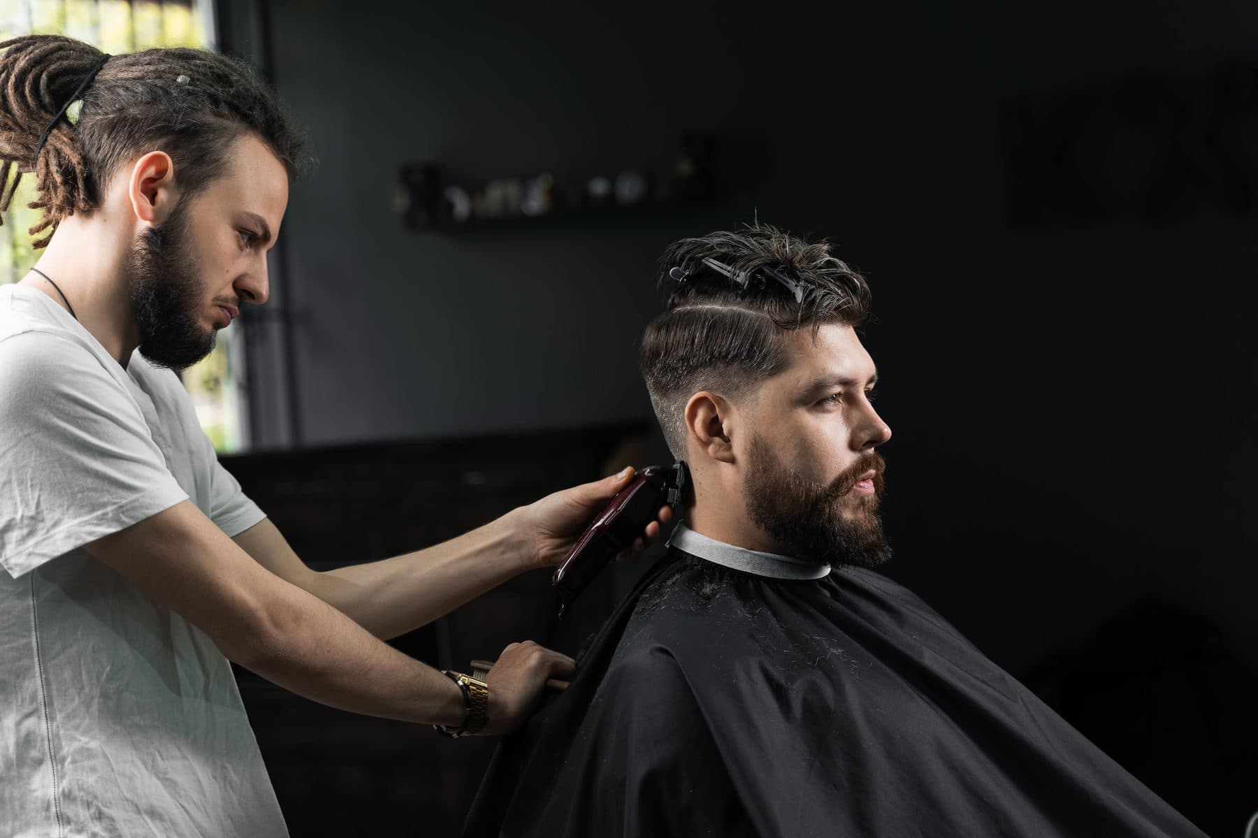 Barber shaping a client's hair under warm shop light
